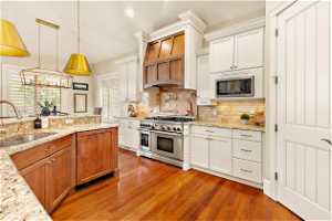 Kitchen with built in microwave, double oven range, sink, hardwood / wood-style flooring, and tasteful backsplash