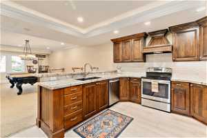 Kitchen featuring light carpet, kitchen peninsula, appliances with stainless steel finishes, custom range hood, and billiards