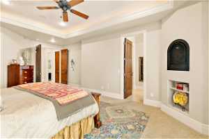 Bedroom featuring carpet flooring, ensuite bathroom, ceiling fan, and a tray ceiling