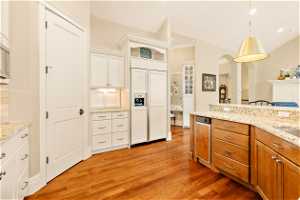 Kitchen with paneled fridge, light hardwood / wood-style flooring, white cabinetry, and pendant lighting
