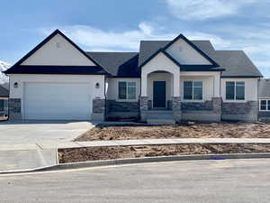 View of front of house featuring stone siding, concrete driveway, and a garage