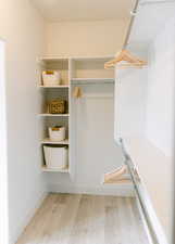 Walk in closet with wood-type flooring