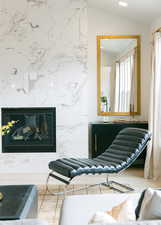 Sitting room with vaulted ceiling, a high end fireplace, and tile walls