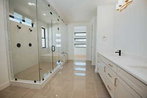 Bathroom with vanity, tile patterned floors, plenty of natural light, and a shower with shower door