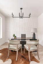 Dining area with a textured ceiling, an inviting chandelier, and light hardwood / wood-style flooring