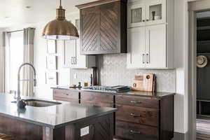 Kitchen featuring stainless steel gas stovetop, sink, dark brown cabinets, and white cabinets