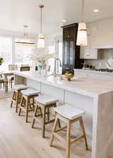 Kitchen with decorative light fixtures, a breakfast bar area, and a healthy amount of sunlight