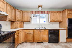 Kitchen with light tile floors, black appliances, and sink