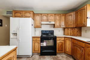 Kitchen with white refrigerator with ice dispenser, light tile floors, and black electric range