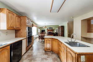 Kitchen with light tile floors, sink, hanging light fixtures, black appliances, and baseboard heating