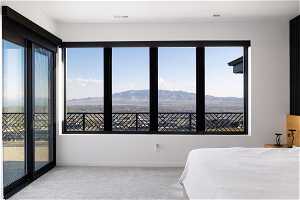 Carpeted bedroom with a mountain view, multiple windows, and access to exterior
