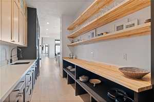Kitchen with light hardwood / wood-style flooring, wooden counters, and sink