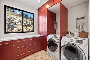 Clothes washing area with washer hookup, washing machine and clothes dryer, cabinets, and light tile flooring
