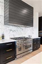 Kitchen with range with two ovens, light hardwood / wood-style flooring, backsplash, and custom exhaust hood