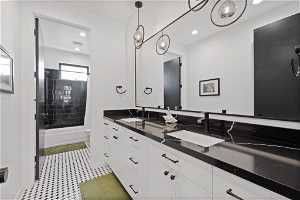 Full bathroom with vanity with extensive cabinet space, dual sinks, shower / tub combo, toilet, and tile floors