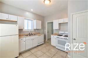 Kitchen with white cabinetry, white appliances, sink, and light tile flooring2431 B Ave