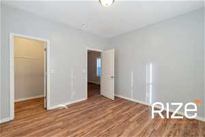 Unfurnished bedroom with wood-type flooring, a walk in closet, and a closet2431 B Ave