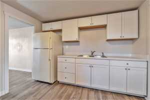 Kitchen with white refrigerator, sink, light wood-type flooring, and white cabinetry564 Capitol St