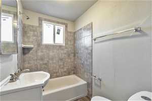 Full bathroom featuring tiled shower / bath combo, toilet, vanity, and a textured ceiling564 Capitol St