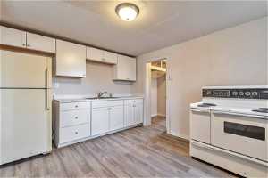 Kitchen featuring white cabinetry, light hardwood / wood-style floors, white appliances, and sink564 Capitol St