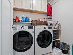 Clothes washing area featuring independent washer and dryer and cabinets