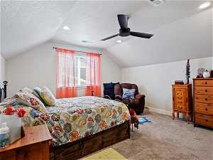 Bedroom with ceiling fan, vaulted ceiling, carpet, and a textured ceiling