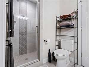 Bathroom featuring an enclosed shower, toilet, and tile floors
