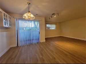 Spare room featuring rail lighting, hardwood / wood-style floors, and an inviting chandelier