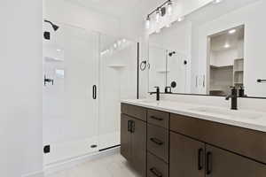 Bathroom featuring tile flooring, an enclosed shower, and double vanity.  Upgraded