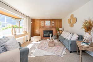 Carpeted living room featuring wood walls and a brick fireplace