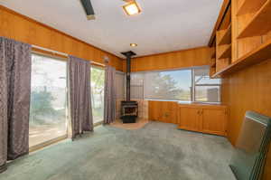 Interior space featuring wood walls, a wood stove, and crown molding