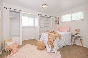 Carpeted bedroom featuring a closet and multiple windows