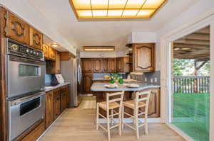 Kitchen featuring a kitchen bar, sink, light hardwood / wood-style floors, stainless steel appliances, and kitchen peninsula