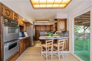 Kitchen featuring a kitchen bar, sink, light hardwood / wood-style floors, stainless steel appliances, and kitchen peninsula