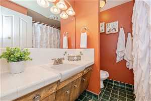 Bathroom featuring tile flooring, backsplash, vanity, and toilet
