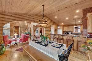 Dining room with wood ceiling, light hardwood / wood-style flooring, log walls, and lofted ceiling