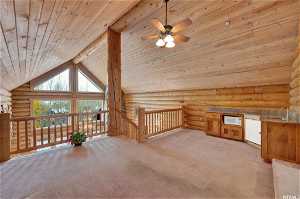 Bonus room featuring light colored carpet, high vaulted ceiling, and rustic walls