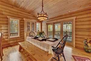 Dining space featuring light hardwood / wood-style floors, log walls, wooden ceiling, and lofted ceiling