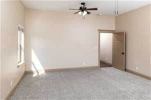 Empty room with a healthy amount of sunlight, ceiling fan, and carpet flooring