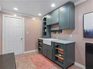 Kitchenette with crown molding, light tile floors, and sink