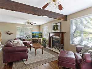 Living room featuring beamed ceiling, wood-type flooring, and ceiling fan