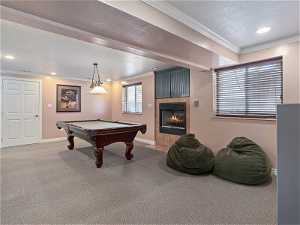 Recreation room featuring a textured ceiling, pool table, a tiled fireplace, and carpet flooring
