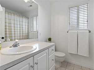 Bathroom featuring a healthy amount of sunlight, toilet, tile floors, and vanity