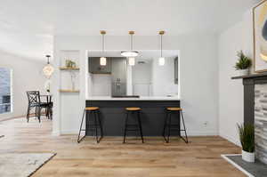 Kitchen featuring gray cabinets, a kitchen breakfast bar, LVP wood-style floors, and kitchen peninsula