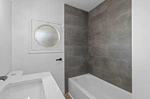 Bathroom with sink, tiled shower / bath combo, and a textured ceiling