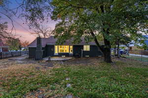 Back house at dusk with a lawn, central AC unit, and a patio