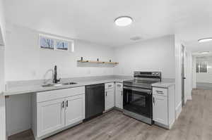 Kitchen featuring LVP wood-style flooring, white cabinetry, sink, range with electric cooktop, and dishwasher