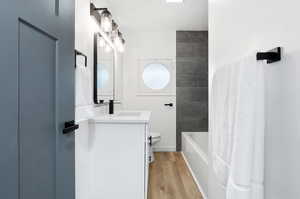 Full bathroom with LVP wood-style floors, tiled shower / bath, vanity, and toilet