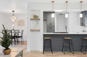 Kitchen with hanging light fixtures, LVP wood-style flooring, and gray cabinets