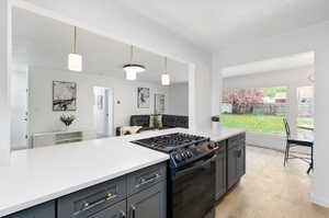 Kitchen featuring decorative light fixtures, black gas range oven, and light wood-type flooring